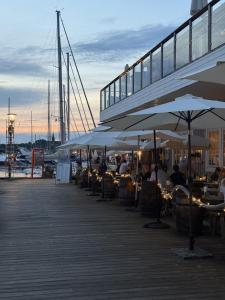 a boardwalk with tables and umbrellas on a pier at GrebbestadFjorden stugor in Grebbestad