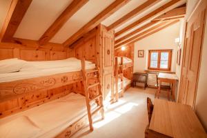 a bedroom with two bunk beds and a desk at Chalet Gulas - La Punt-Chamues-ch in La Punt-Chamues-ch