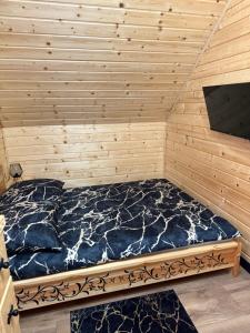a bed in a room with a wooden wall at Domek w górach in Załuczne