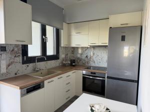 a kitchen with white cabinets and a stainless steel refrigerator at Flâneur apartments in Ormos Panagias