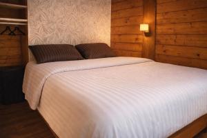 a bedroom with a large white bed with wooden walls at Boshuisje in Enschede