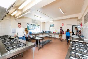 a group of people in a kitchen preparing food at Billabong Backpackers Resort in Perth