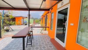 an orange building with a wooden table and a bar at Thung Setthi Homestay&Cafe5 in Chiang Dao