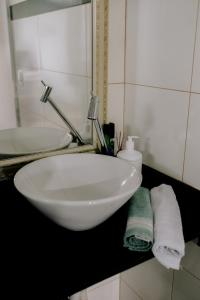 a bathroom with a white sink and towels on a counter at Joia do Pepira in Brotas