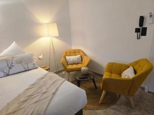 a bedroom with a bed and two chairs and a lamp at L'auberge Camarguaise in Saintes-Maries-de-la-Mer
