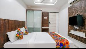 a bedroom with a white bed with a tv on the wall at Hotel Krishna Inn in Bhiwandi