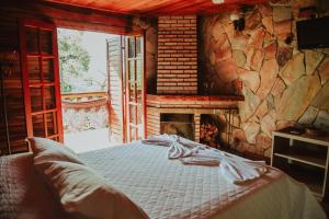 a bedroom with a bed in front of a fireplace at Pousada Peterle in Domingos Martins