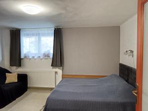 a bedroom with a bed and a couch and a window at Káli Apartman in Bakonybél