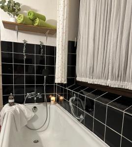 a bath tub in a bathroom with black tiles at Zimmer, Apartment A3 in Offenberg