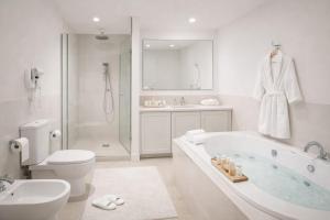 a white bathroom with a tub and a toilet and a sink at Ali House in Lahore