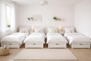 a white bedroom with four beds and a rug at Ali House in Lahore