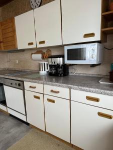 a kitchen with white cabinets and a microwave at Zimmer, Apartment A3 in Offenberg