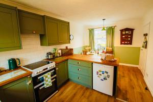 a kitchen with green cabinets and a white stove top oven at Chapel Bricks in Withernwick