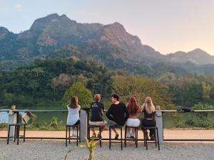 a group of people sitting on a bench looking at the mountains at The Sun Backpackers Hostel in Nongkhiaw +36 photos
