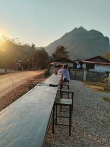 a group of people sitting on benches on a road at The Sun Backpackers Hostel in Nongkhiaw