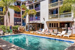 a group of people sitting in lounge chairs by a swimming pool at Billabong Backpackers Resort in Perth