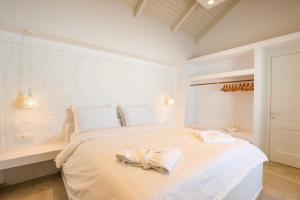 a white bedroom with a large bed with towels on it at Manos Villas in Karpathos +27 photos