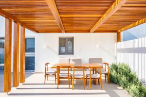 a wooden patio table and chairs under a wooden pergola at Manos Villas in Karpathos
