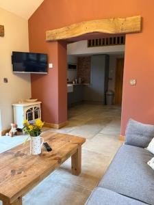 a living room with a wooden table and a couch at Y Beudy Bach in Llanfor