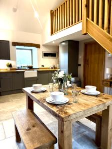 a wooden table with plates and bowls on it in a kitchen at Y Beudy Bach in Llanfor +20 photos
