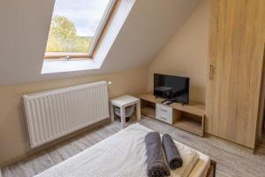 a bedroom with a bed and a tv and a window at Forrás Panzió és Apartman in Orfű