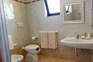 a bathroom with a toilet and a sink and a mirror at Agriturismo Residence Molle con piscina in Carpignano Salentino
