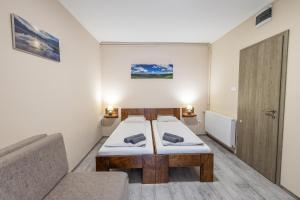 a small room with two beds and a couch at Forrás Panzió és Apartman in Orfű