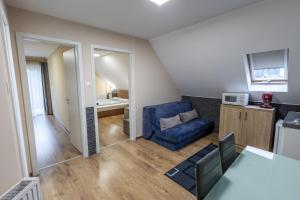 a living room with a blue couch and a kitchen at Forrás Panzió és Apartman in Orfű