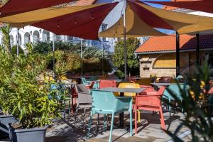 a patio with colorful chairs and tables and umbrellas at Forrás Panzió és Apartman in Orfű