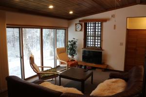 a living room with a couch and a table at Kamoshika Cottage Hakuba in Hakuba