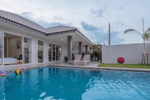 a swimming pool in front of a house at 63 Jomtien Beach villa วิลล่าใกล้หาดจอมเทียน 這棟別墅距離海灘不遠 in Jomtien Beach