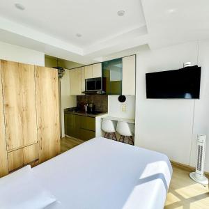 a bedroom with a white bed and a kitchen at Exclusive Tiny Loft in Usaquén in Bogotá +2 photos