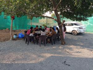 a group of people sitting at a table under a tree at Ranchhod Villa in Marwad