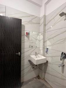 a bathroom with a sink and a black door at ReneeMysa in Indore