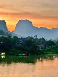 a sunset over a river with boats in the water at Arthith Guesthouse in Nongkhiaw +32 photos