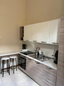 a kitchen with white cabinets and a sink and stools at The Reggia Nest in Caserta