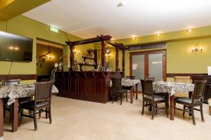 a dining room with tables and chairs and a television at Pension Casa Vanatorilor in Băile Olăneşti