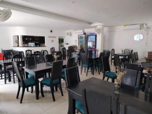 a dining room with black tables and chairs at Hotel Cascada in Ríohacha