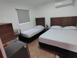 a hotel room with two beds and a tv at Hotel Cascada in Ríohacha