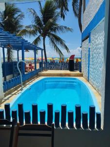 a large swimming pool with chairs and palm trees at Pousada Pé no Mar in Japaratinga