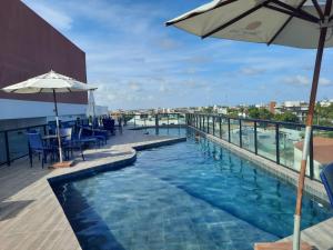 a swimming pool on top of a building with an umbrella at Departamento ideal in Ipojuca