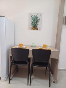 a dining room table with two chairs and a pineapple at Departamento ideal in Ipojuca +1 photo