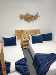 a room with two beds with blue pillows at Pousada Pé no Mar in Japaratinga +16 photos