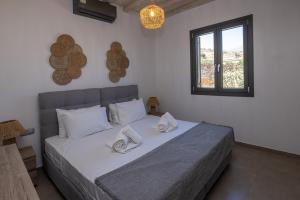 a bedroom with a bed with white sheets and a window at Marilias cycladic home in Agios Fokas