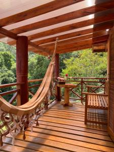 a hammock on a wooden deck with a table and bench at Chalé Recanto Belo. in São Mateus