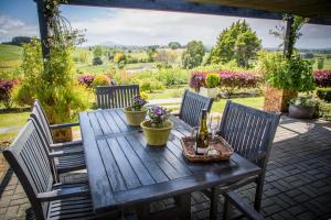 a wooden table with three chairs and a bottle of champagne at Waitomo Orchard Estate B&B in Otorohanga