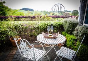 a table with a bottle of wine and two chairs at Waitomo Orchard Estate B&B in Otorohanga