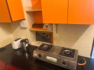 a stove in a kitchen with orange cabinets at Peaceful Pines Cottage in Bhowāli