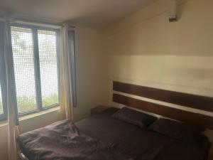 a bedroom with a bed and two windows at Peaceful Pines Cottage in Bhowāli
