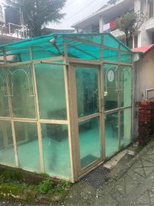 an empty greenhouse with glass doors and water at Peaceful Pines Cottage in Bhowāli